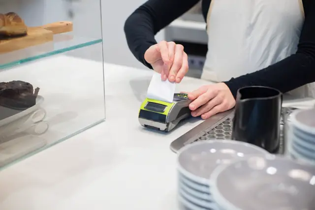 Cajera sacando el comprobante de un terminal de pago
