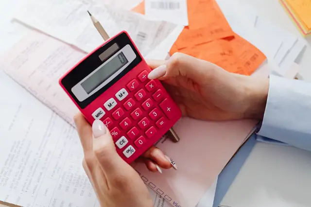Manos con calculadora sobre boletas y papeles