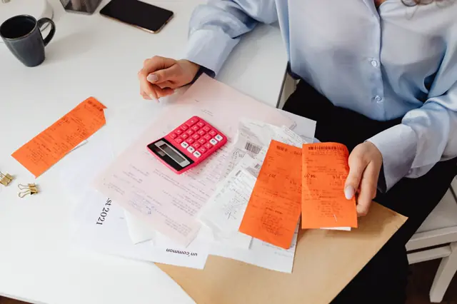 Mesa llena de boletas, papeles y una calculadora